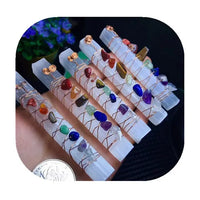 A person displays a collection of crystal rods, each featuring different colored stones, highlighting their beauty and diversity.