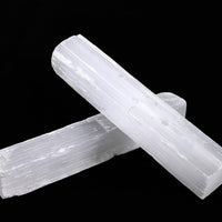 Two white quartz rods, identified as selenite crystal wands, displayed against a contrasting black background.