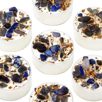 Six candles surrounded by blue and white stones, creating a serene and decorative display.